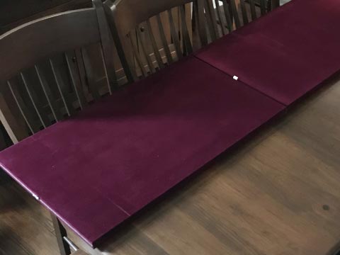 Table protector pad folded to show burgundy velour underside